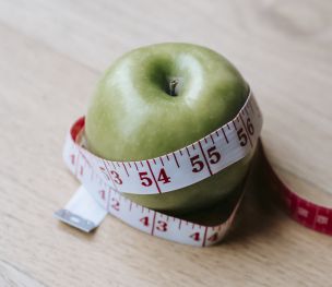 Green apple with measuring tape on table in kitchen