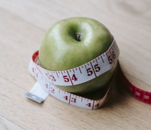 Green apple with measuring tape on table in kitchen